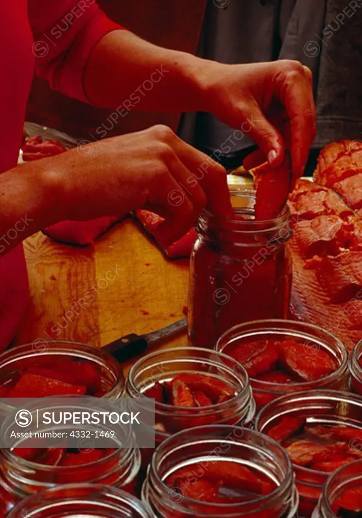 Cheryl Bloethe Linder placing smoked salmon strips in canning jars, Port Alsworth, Alaska.