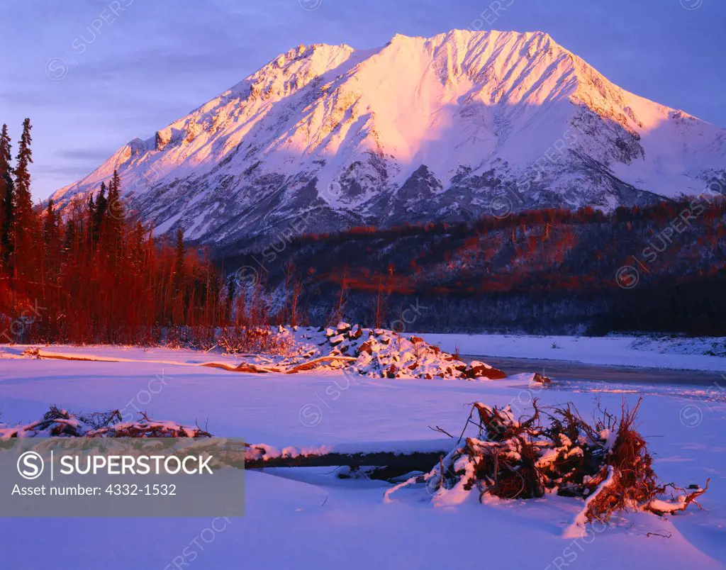 Sunset light illuminating King Mountain viewed from the shore of the Matanuska River in winter, Chugach Mountains, Alaska.
