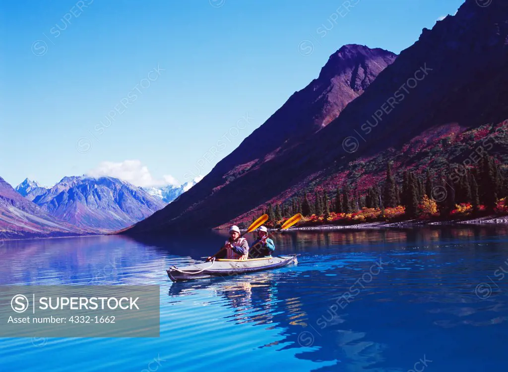 Monroe Robinson and K Schubeck kayaking on glassy water of Upper Twin Lake, Lake Clark National Park, Alaska.