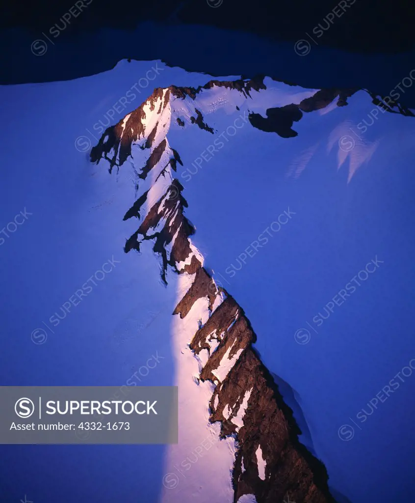 Aerial view of light from the setting sun illuminating ridge or nunatak emerging from the Harding Icefield west of McCarty Fjord, Kenai Fjords National Park, Alaska.