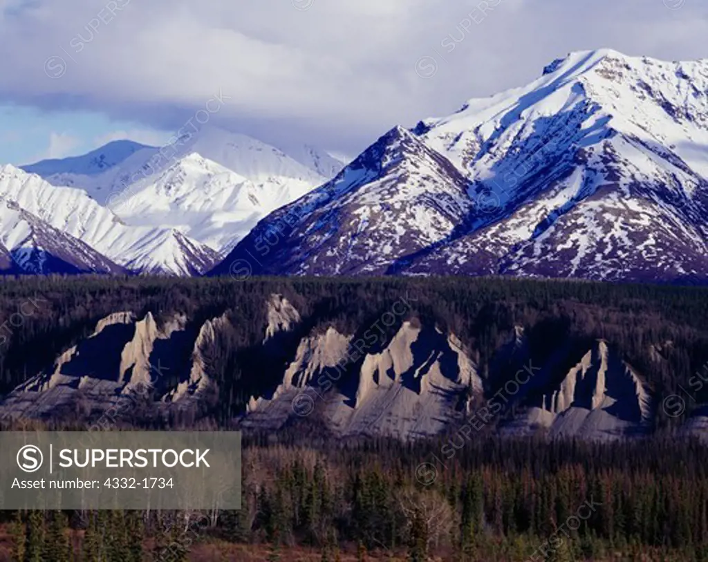 Spring view of eroded bluffs above the Matanuska River and the snow-cover Chugach Mountains adjacent to Glacier Creek, Alaska.