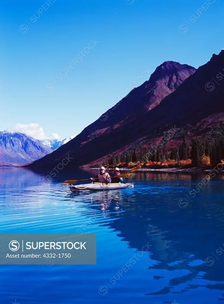 Monroe Robinson and K Schubeck kayaking on glassy water of Upper Twin Lake, Lake Clark National Park, Alaska.