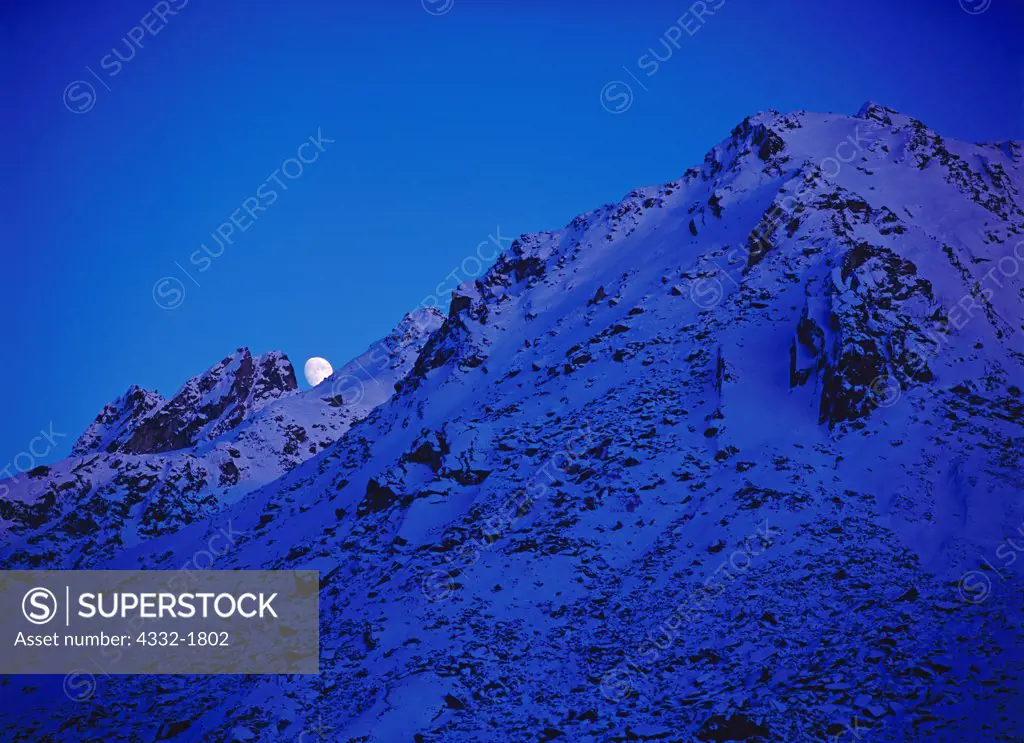 Gibbous moon rising above the Talkeetna Mountains at dusk, Archangel Valley, Alaska.