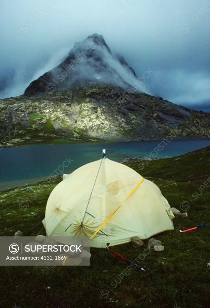 Northface VE24 Dome Tent anchored on tundra with 27 boulders and two ice axes during storm in the Aleutian Range at unnamed lake between Currant Creek and the Tuxedni Glacier, Lake Clark National Park, Alaska.
