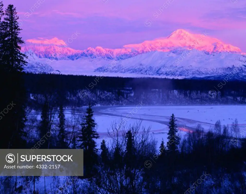 Warm light of a winter sunrise illuminating Mount Hunter and Mount McKinley towering above the Chulitna River and Ruth Glacier, Denali State Park and Denali National Park, Alaska.