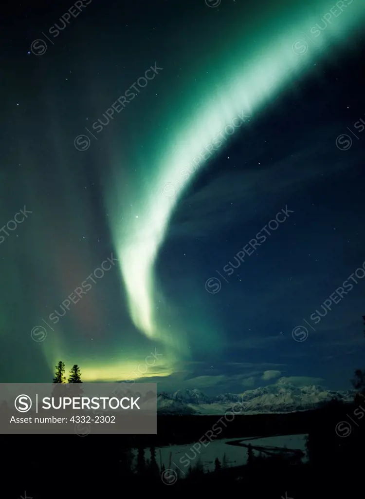 Beautiful display of northern lights arcing over the Alaska Range including Mount McKinley or Denali with the Chulitna River in the foreground, Denali State Park, Alaska.