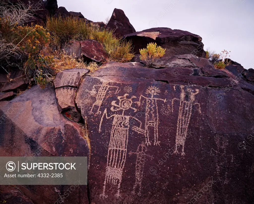 Coso Range Style petroglyphs of highly decorated anthropomorphs carved on a basalt wall, Renegade Canyon, Naval Air Weapons Station, China Lake, California.