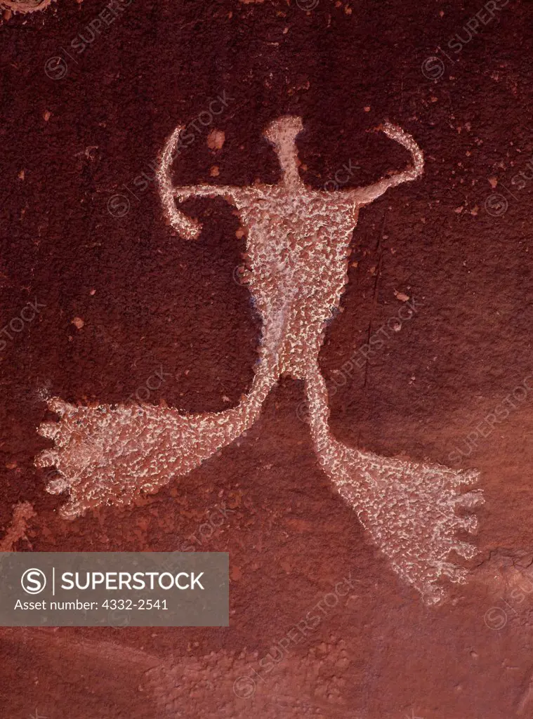 Petroglyph of large-footed anthropomorph with bow, sandstone cliff above Indian Creek, Southeastern Utah.