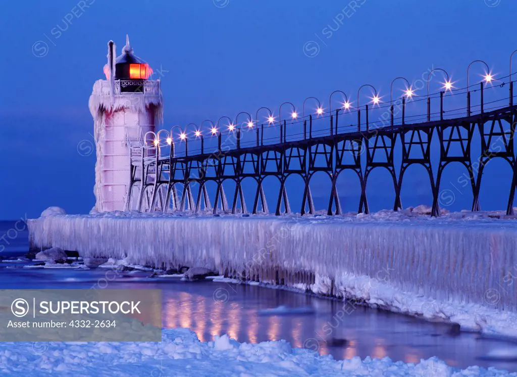 Ice-covered South Haven Pier Lighthouse illuminated at dawn, mouth of the Black River into Lake Michigan, South Haven, Michigan.