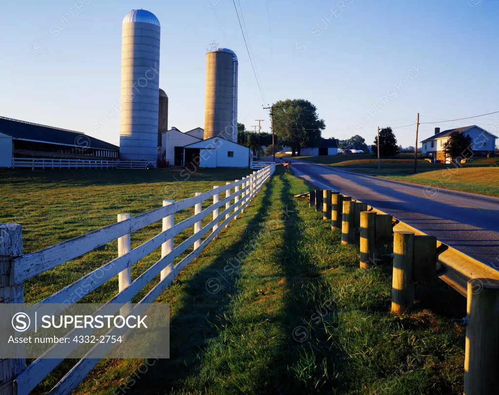 Sunrise illuminating silos and fence along farm on Highway 557 west of Berlin, Ohio.