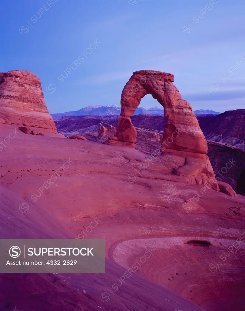 Pastel light of dusk illuminating Delicate Arch with the LaSal Mountains beyond, Arches National Park, Utah.