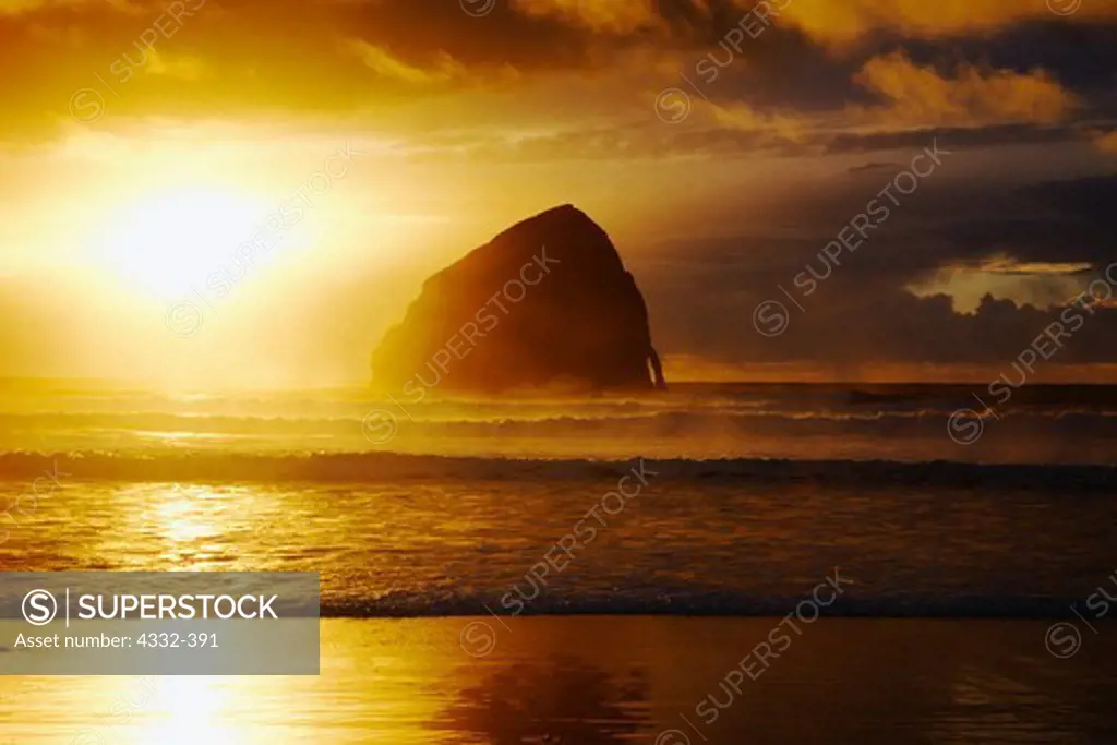 A sunset breaks through a storm at Haystack Rock at Cape Kiwanda on the coast of Oregon.