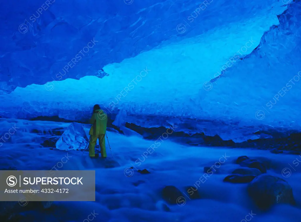 Jeff Gnass photographing iceberg in middle of stream flowing through glacial ice cave in remnant of the Muir Glacier, Glacier Bay National Park, Alaska.