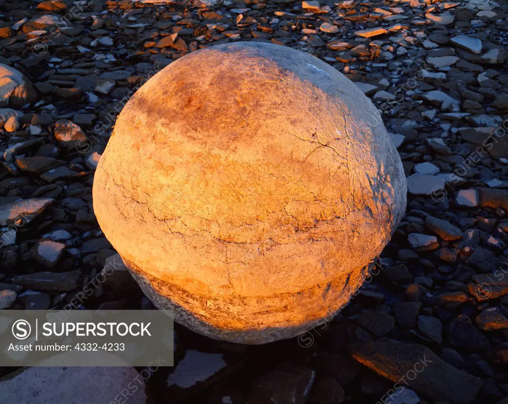 Large spherical concretion or 'kettle' illuminated by setting sun, shore of Lake Huron at Kettle Point, Ontario, Canada.