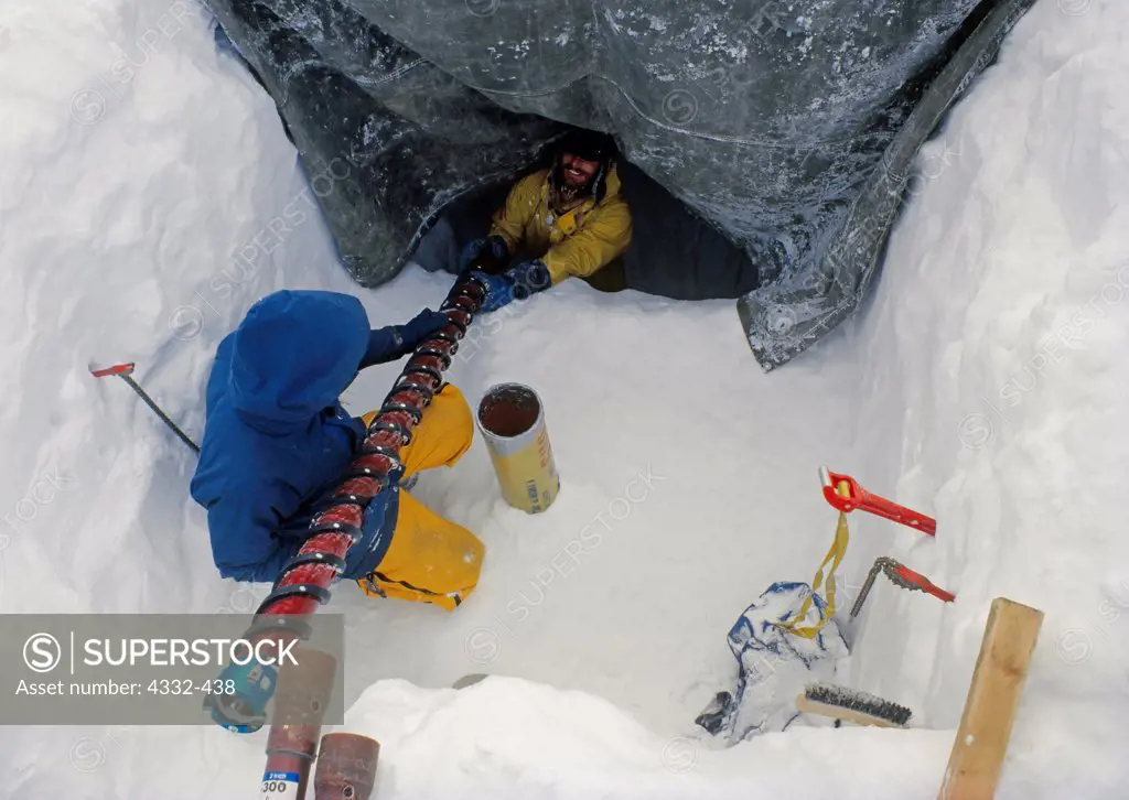 Glacial research in the summit crater of Redoubt Volcano. Bob Gerhard passes an ice core sample to Matthew Sturm, staff from Lake Clark National Park and the Alaska Geophysical Institute, Alaska.