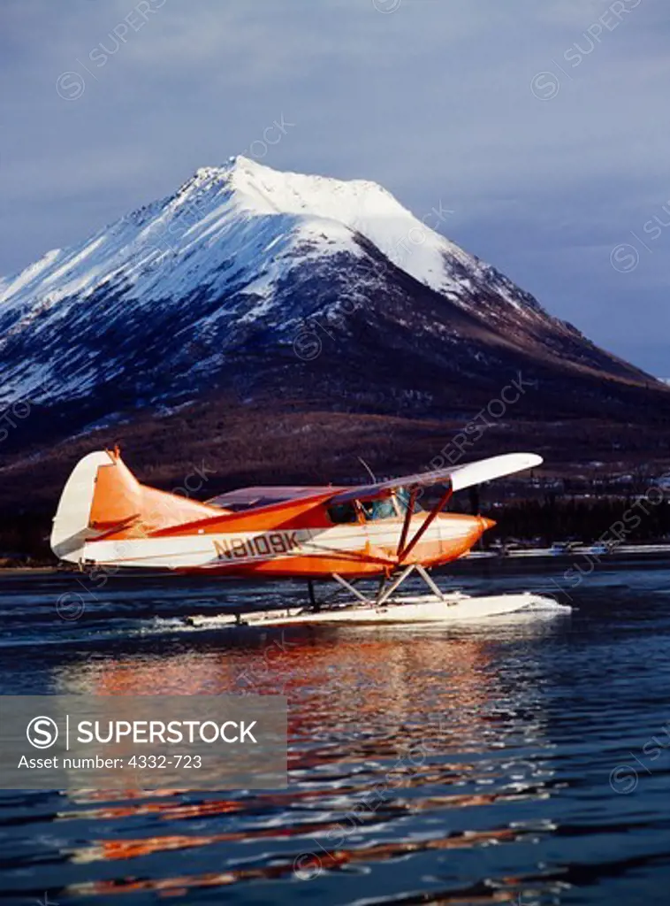 Howard Bowman's Stinson Voyager 108 with a PDX Conversion taxiing on Hardenburg Bay of Lake Clark, Tanalian Mountain beyond, Lake Clark National Park and Preserve, Alaska.