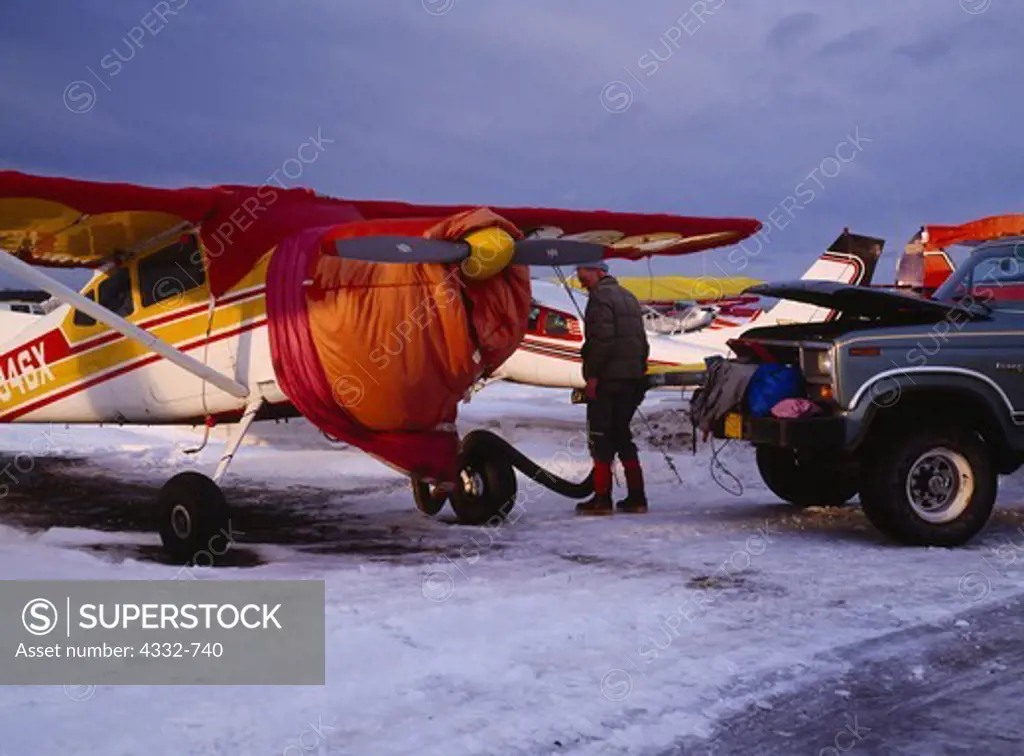 Ed Barber of Anchorage pre-heating the engine of his Cessna 185 on a cold winter day, Ted Stevens Anchorage International Airport, Anchorage, Alaska.