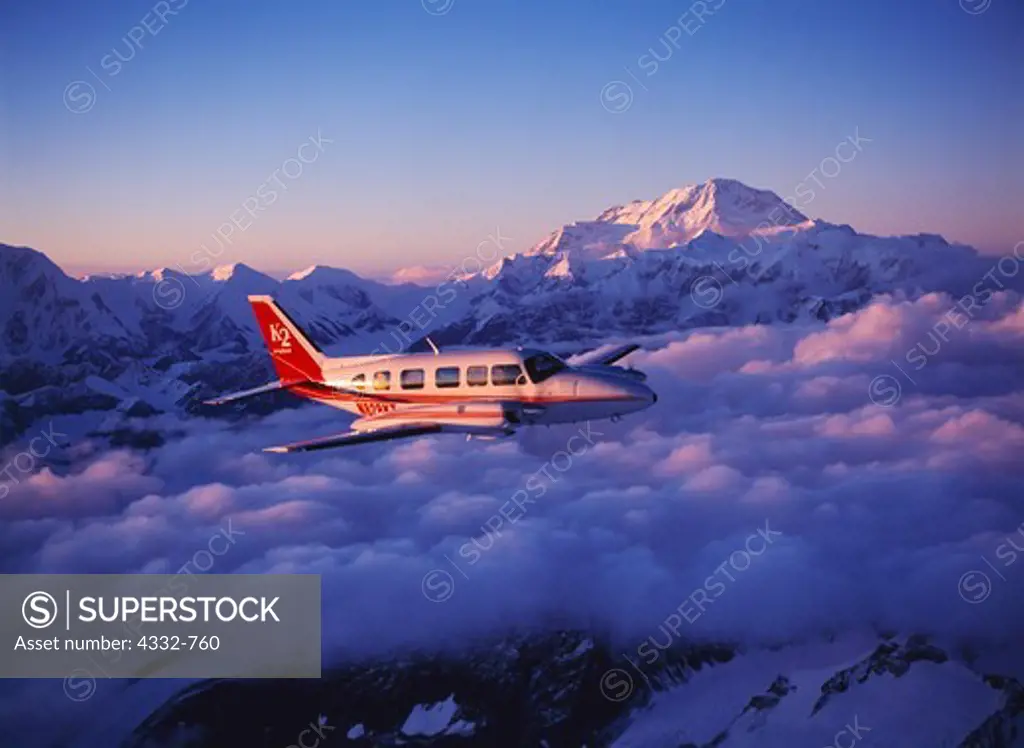 K2 Aviation's Piper Navajo Chieftain flying above clouds east of the Kahiltna Glacier of 20,320 foot Mount McKinley or Denali beyond, Denali National Park, Alaska.