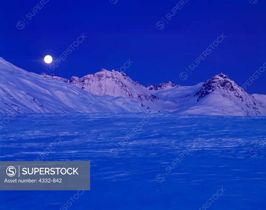 Full moon rising over a wintry Kusawak Range, Northern British Columbia, Canada.