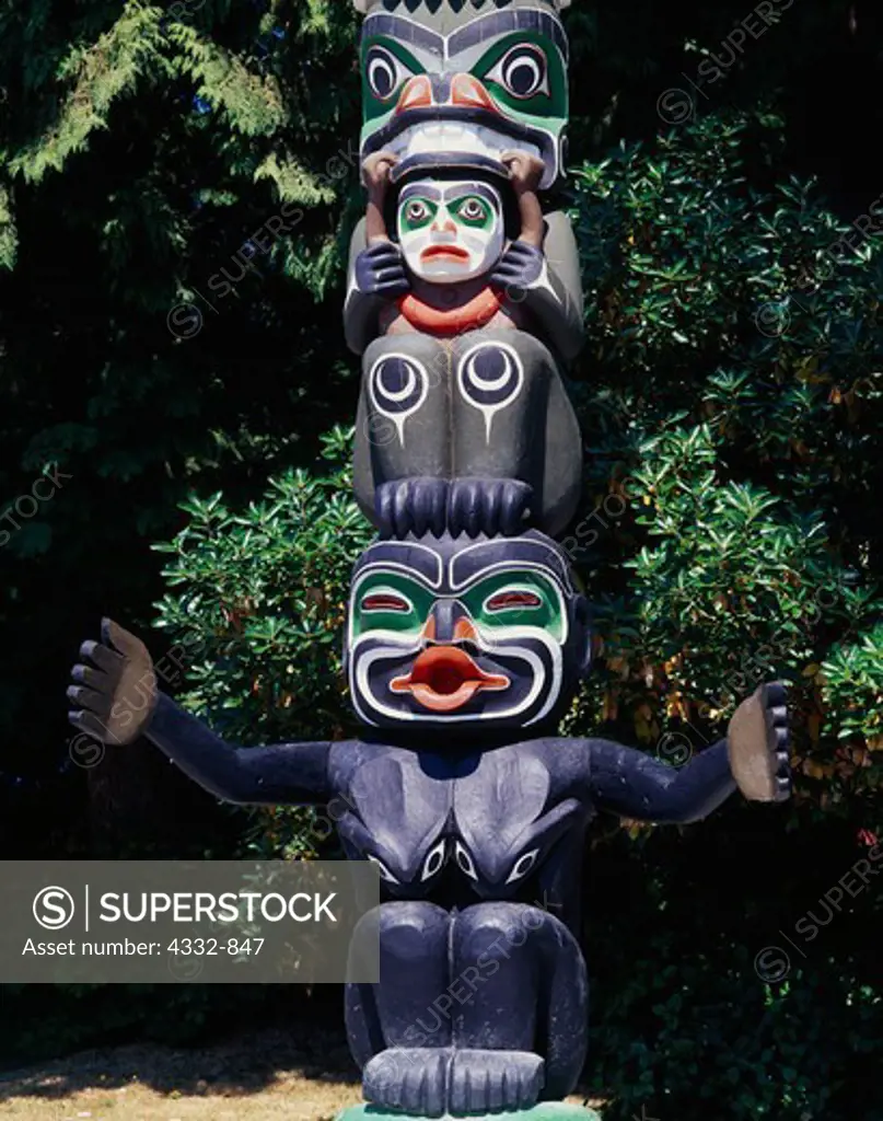 Grizzly Bear over man's head and Dzunukwa, the giantess, figures on the Ga'akstalas Pole, carved by Wayne Alfred and Beau Dick in 1991 and based on a Kwakwaka'wakw design by Russell Smith.  Totem pole on display at Stanley Park, Vancouver, British Columbia, Canada.