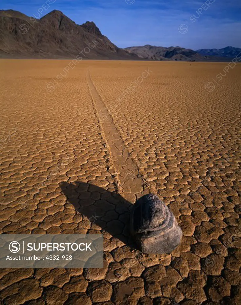 Boulder with trail on the playa surface of the Racetrack. Boulders either move in high winds on slick surface of playa or when embedded in plates of floating ice in winter, Death Valley National Park, California.