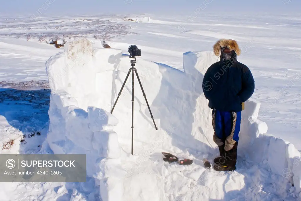 Inupiaq guide stands inside an igloo snow blind used to photograph a polar bear den along the Arctic coast of Alaska in early spring.