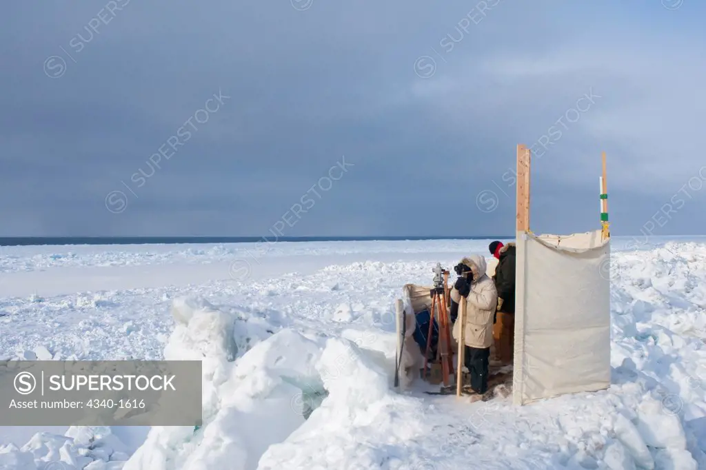 Scientists conducting a bowhead whale (Balaena mysticetus) survey, standing in an observation area in rough pack ice to count passing migrating whales during their Spring migration, on the Chukchi Sea, off shore from Barrow, Alaska.  The survey is conducted every 5 years.