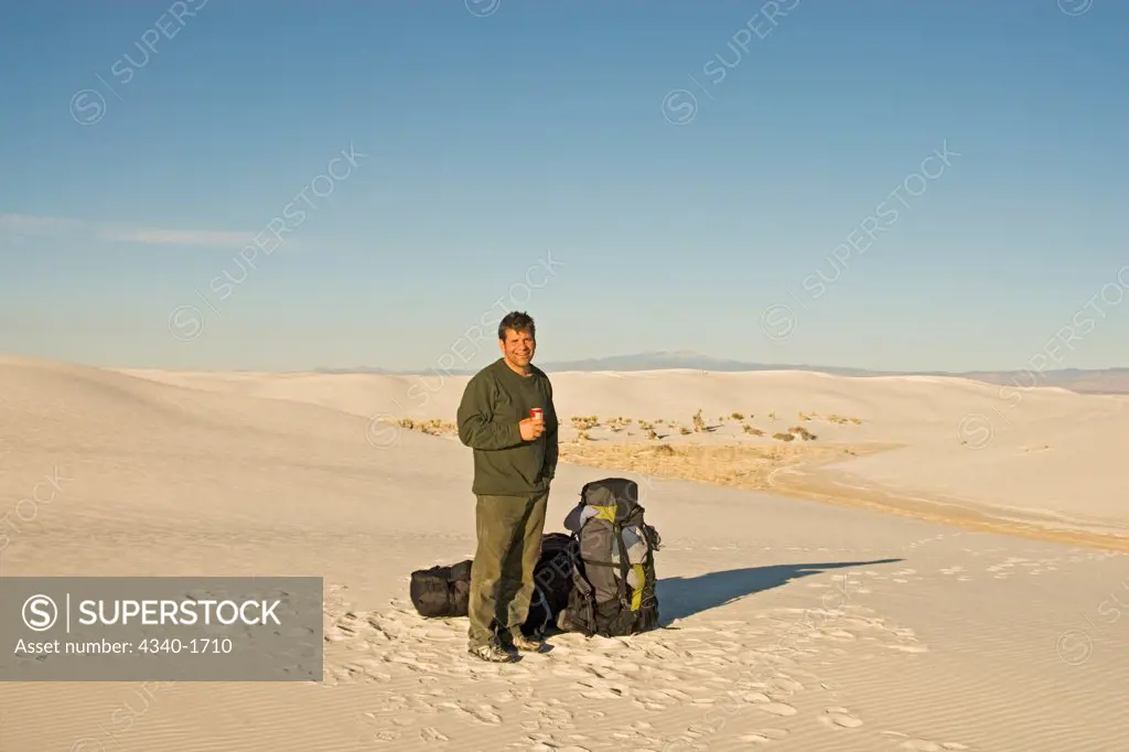 Photographer Steven Kazlowski takes a break from hiking over the glistening white gypsum sand dunes in the Chihuahuan Desert, White Sands National Monument, Tularosa Basin, New Mexico, in wintertime.
