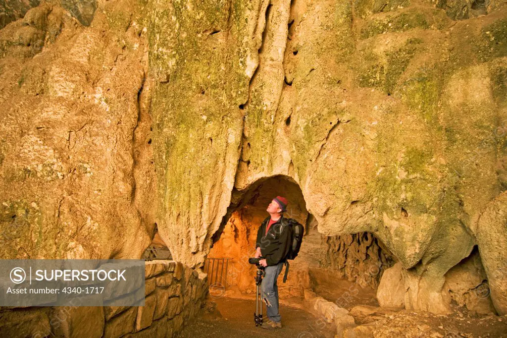 A photographer observes the massive underground formations as he descends into the caves through the Natural Entrance route, Carlsbad Caverns National Park, Chihuahuan Desert, New Mexico.  The Natural Entrance route descends 750 feet into the Earth.