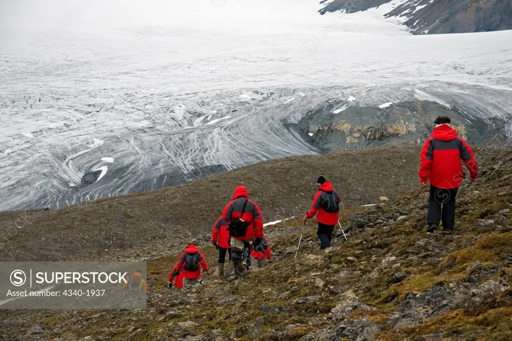 Cruise ship tourists hike to Osbornebreen - a retreating glacier in St. Jonsfjord, west coast of Svalbard, Norway.