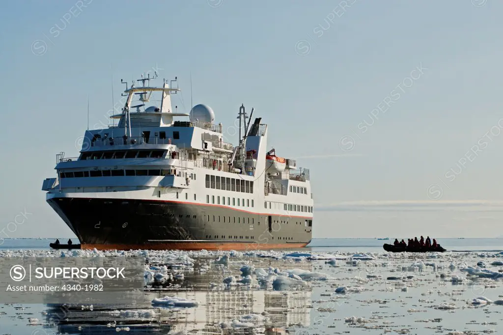 Zodiacs filled with tourists return to cruise ship after venturing out amongst the sea ice to look for wildlife, Freemansund Channel, eastern coast of Svalbard, Norway, in summertime.
