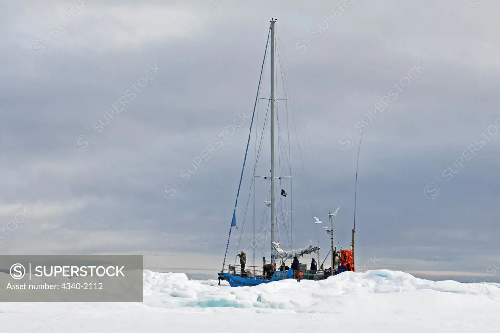 A charter sailboat expedition circumnavigating the Svalbard archipelago in sea ice in early morning, Norway.