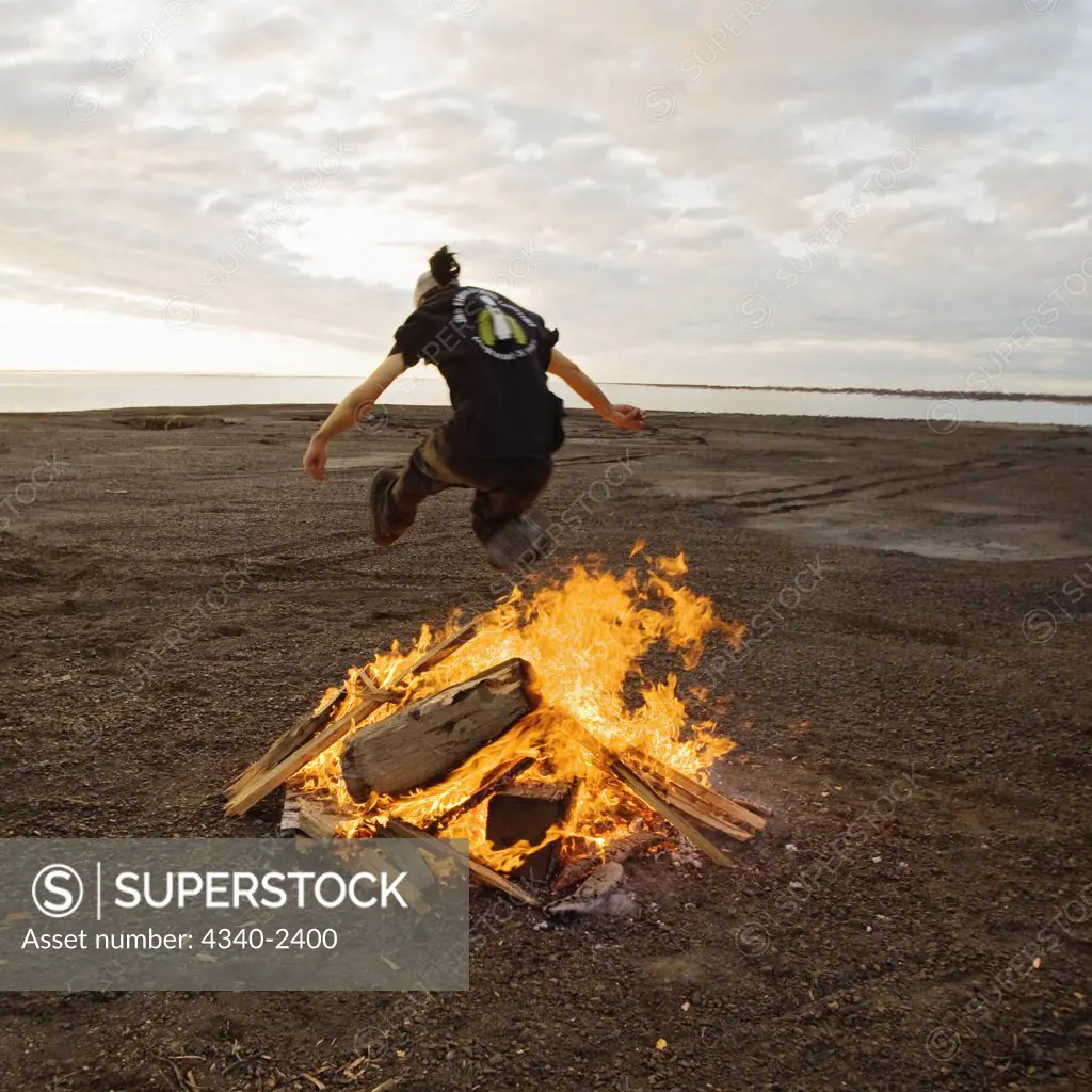 Young Man Leaps Over Campfire
