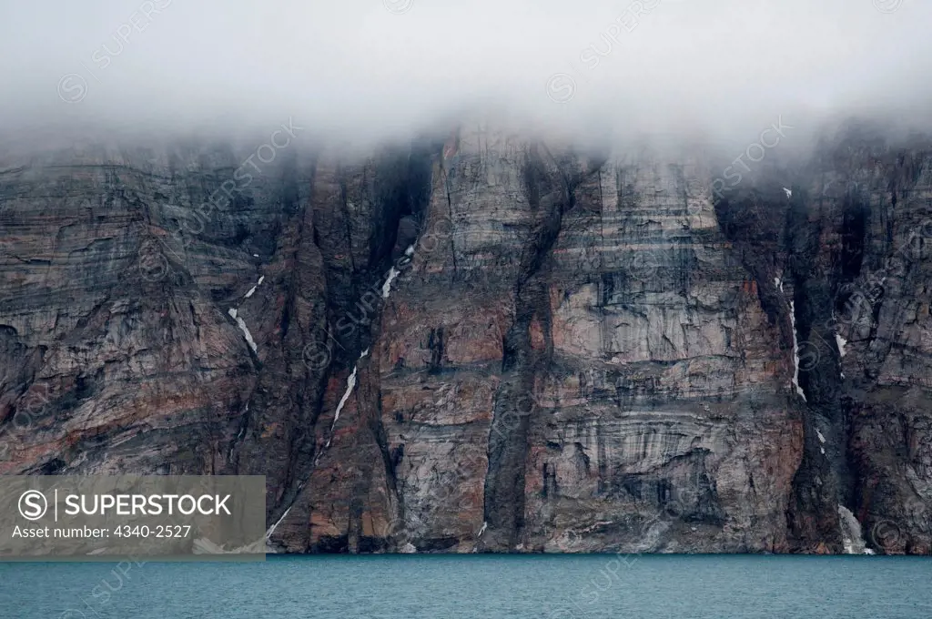 Fog layer floats just above a steep cliff side on the northwest corner of Baffin Island, Northwest Passage in August, Nunavut, high arctic in Canada