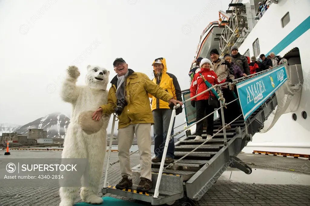 Norway, Svalbard Archipelago, Spitsbergen, Ny Alesund, Passengers disembarking from cruise ship posing with costumed Polar bear