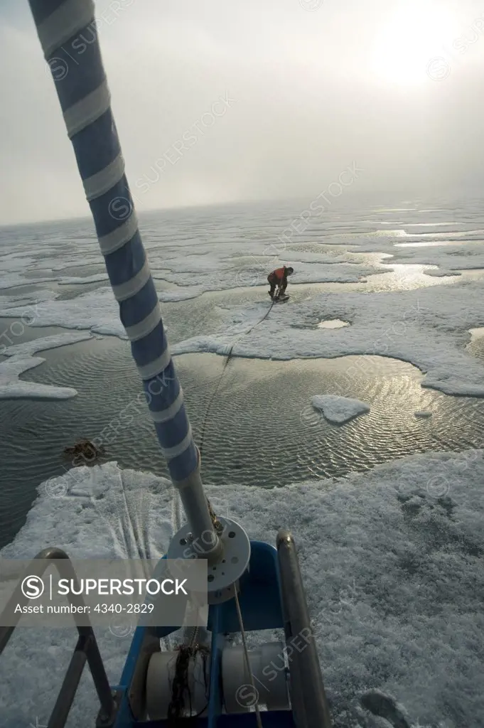 Norway, Svalbard Archipelago, Sailboat captain dropping anchor in fjord ice along northwest coast of Spitsbergen