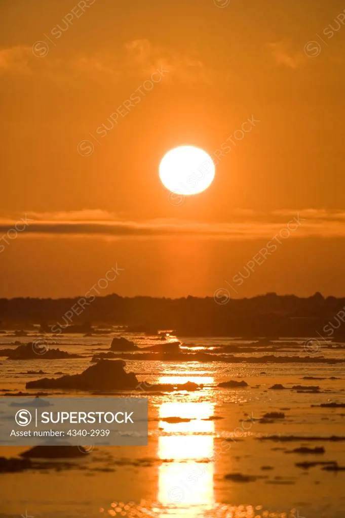 USA, Alaska, Chukchi Sea, offshore from Barrow, Sun glowing brightly over Chukchi Sea, silhouetting ice floes