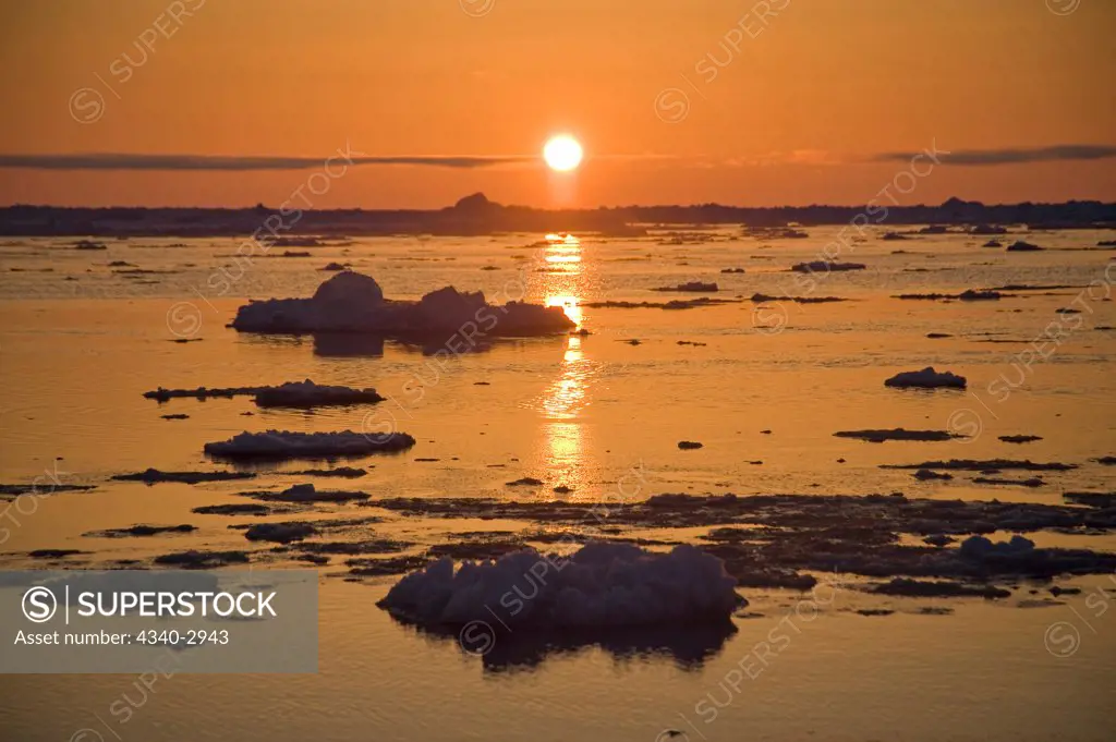 USA, Alaska, Chukchi Sea, offshore from Barrow, Sun glowing brightly over Chukchi Sea, silhouetting ice floes