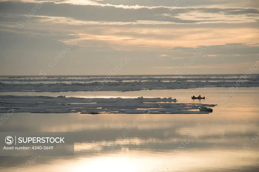 USA, Chukchi Sea, Alaska, Barrow, Inupiaq subsistence whaling crew use motorboat in open lead as they look for passing bowhead whales during spring whaling season, Arctic coast of Alaska