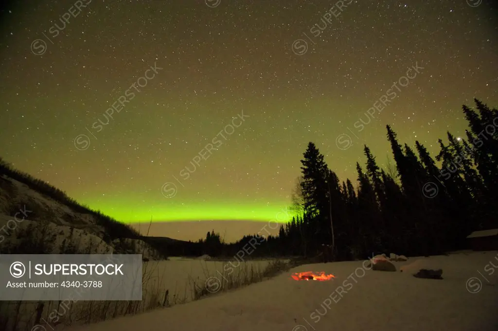 USA, Alaska, Recreational Area, Chena River State, Northern lights (Aurora borealis) glowing brightly over campfire