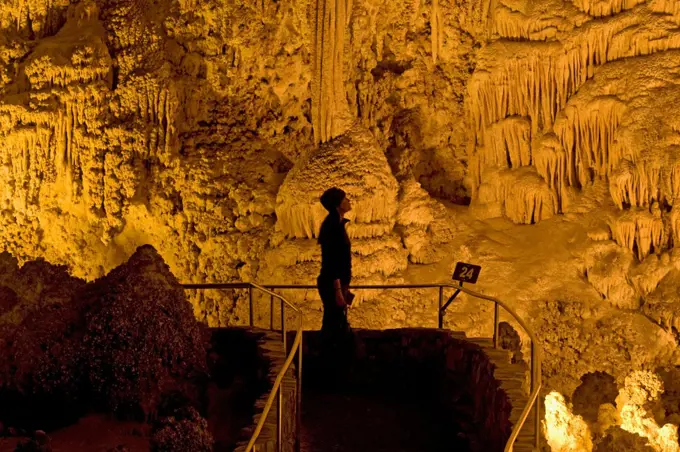 A tourist observes the massive underground formations in the wondrous 8.2-acre Big Room cave, 750 feet into the Earth, Carlsbad Caverns National Park, Chihuahuan Desert, New Mexico.