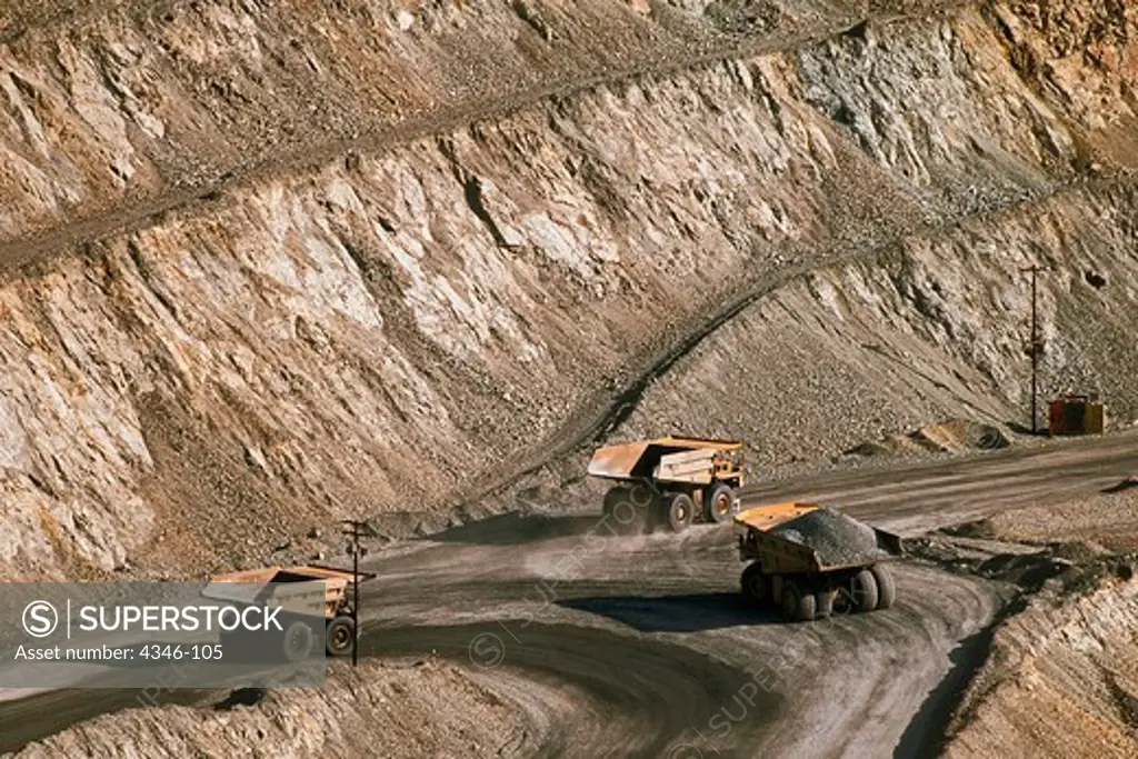 Enormous Mining Trucks Are Dwarfed by an Open Pit Mine