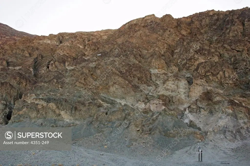 A rugged barren rocky hillside in Death Valley National Park, California. Death Valley is the lowest point in North America, 282 feet below sea level. This hillside is above the lowest point in Death Valley, Badwater Basin. The small white line two thirds of the way up the cliff is a sign reading 'Sea Level'.