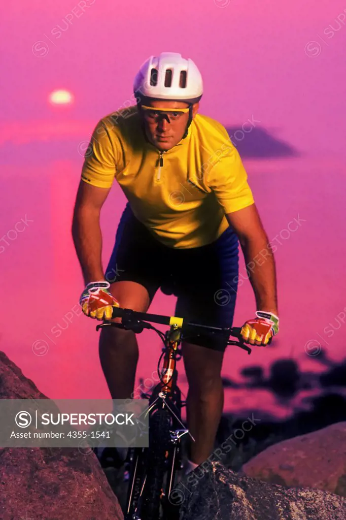 A man riding a mountain bike at sunset, Gloucester, Massachusetts.
