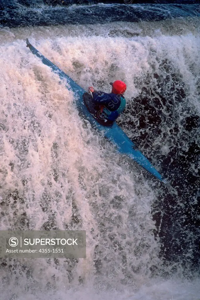 A kayaker kayaks over a waterfall.
