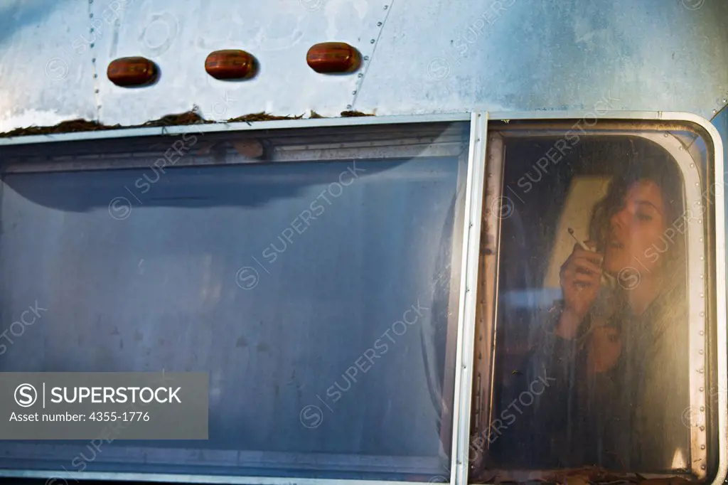 A woman smoking in a old Airstream trailer.