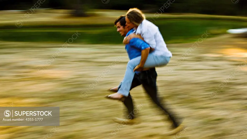 A man carrying his girlfriend across a field in Mendocino, California.