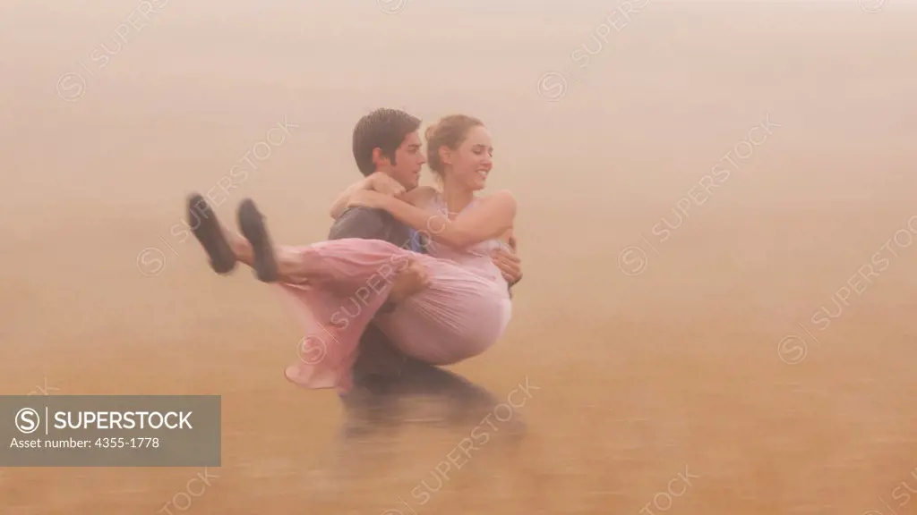 A man carrying his girlfriend across a field in Mendocino, California.