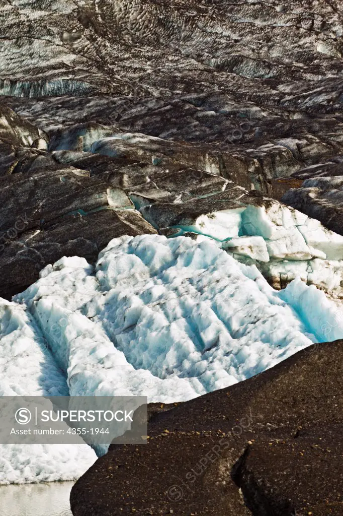 Located in South Eastern Iceland, Svinafellsjokull is one of the many outlet glaciers of the massive Vatnajokull glacier, EarthÆs third-largest. The ice that feeds Svinafellsjokull comes spilling down from Icelandæs high interior in an icefall that riddles it with deep crevasses. Much of the glacier is covered with interwoven layers of black ash from recent volcanic eruptions.