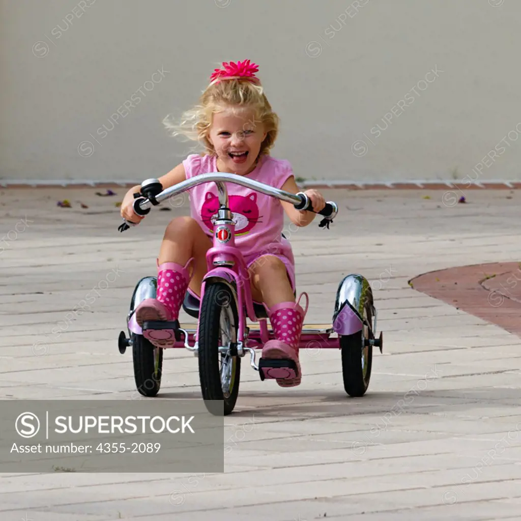 Little girl riding tricycle with gusto.